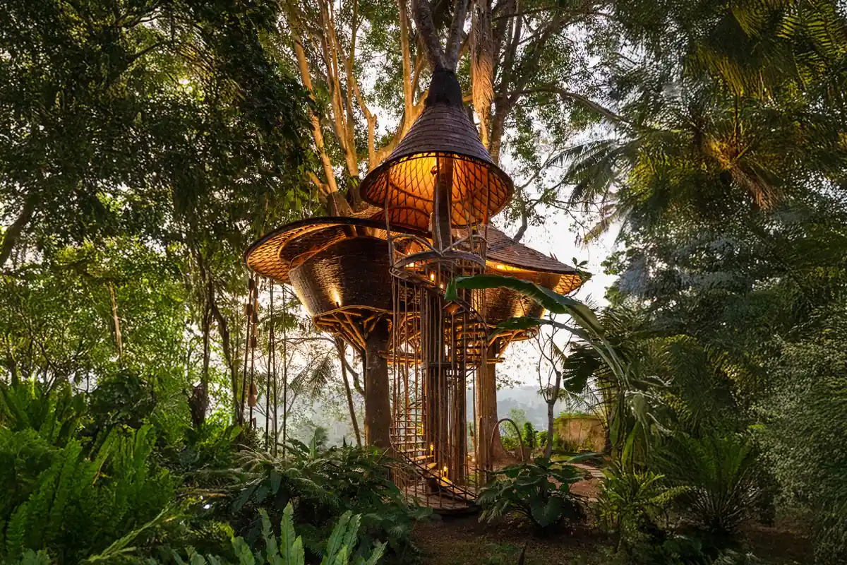 A bamboo tree house lit up at dusk in the jungle at Bambu Indah, Sayan, Ubud