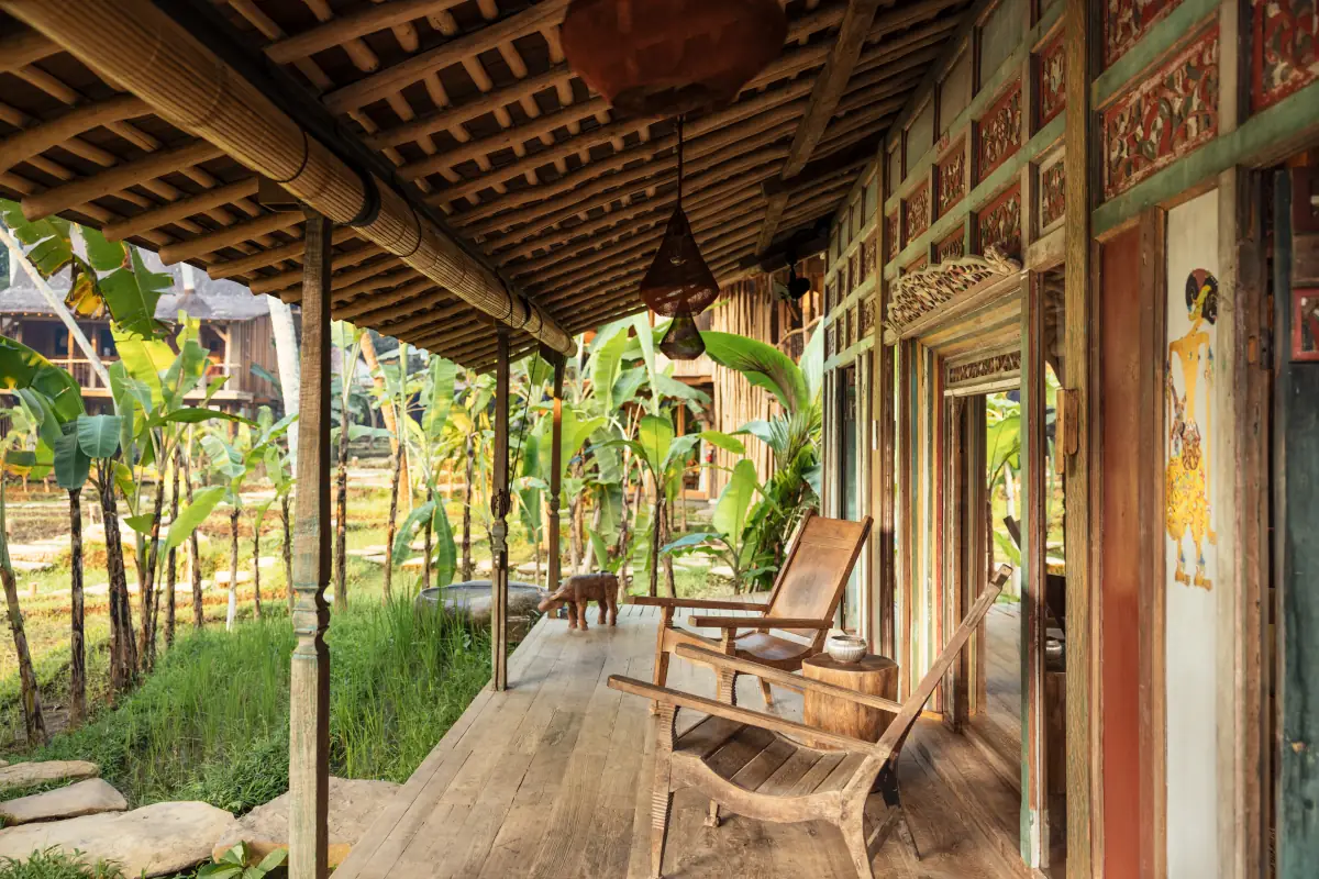 The carved veranda of an antique Javanese teak house beside the rice fields at Bambu Indah